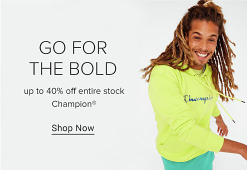 A man wearing a neon hoodie with the Champion logo on the front and green shorts. Go for the bold. Up to 40% off entire stock Champion. Shop now.